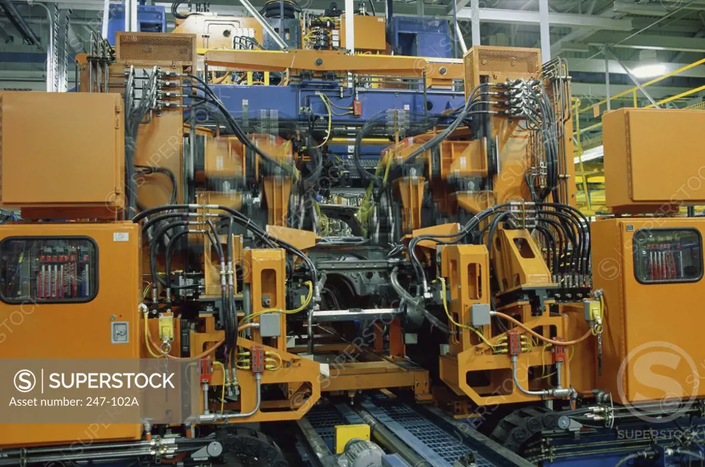 Cars on a production line being assembled by robotic arms