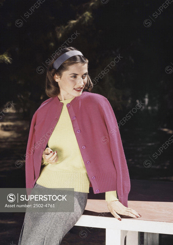 Stock Photo: 2502-4761 Young woman leaning on a bench and smiling