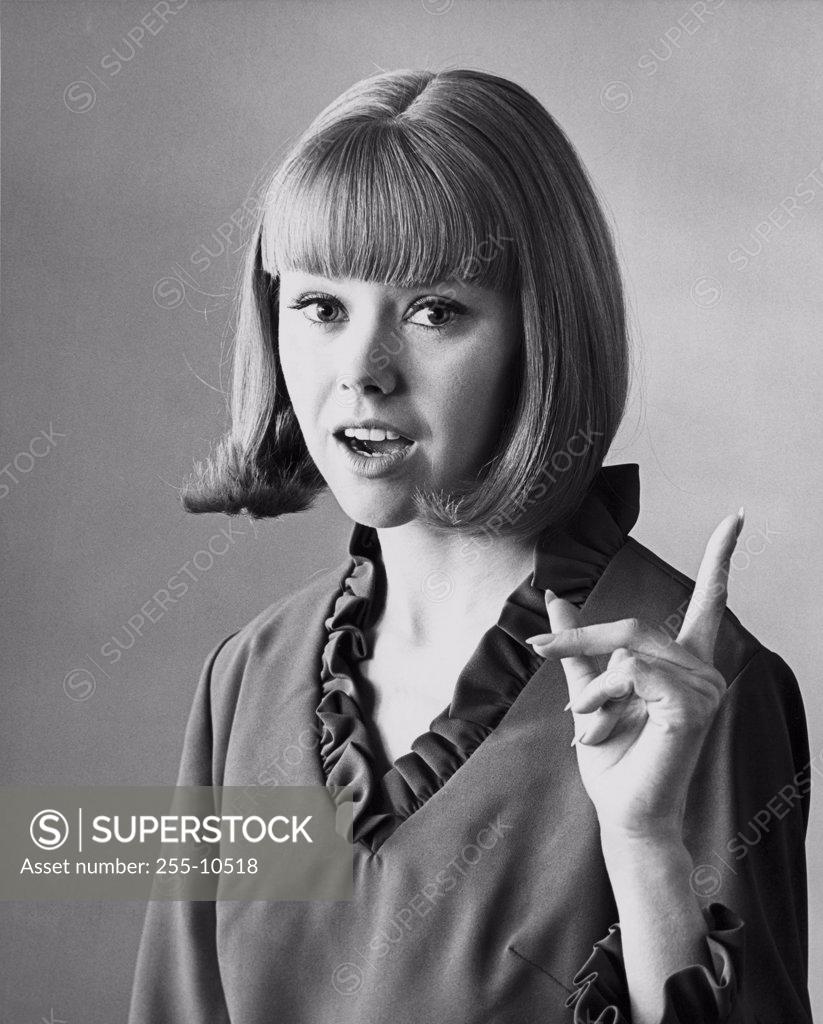 Stock Photo: 255-10518 Portrait of a young woman pointing upward