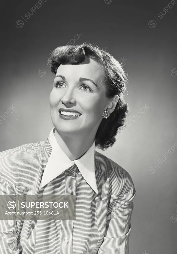 Brunette woman wearing striped blouse with white collar looking up and smiling