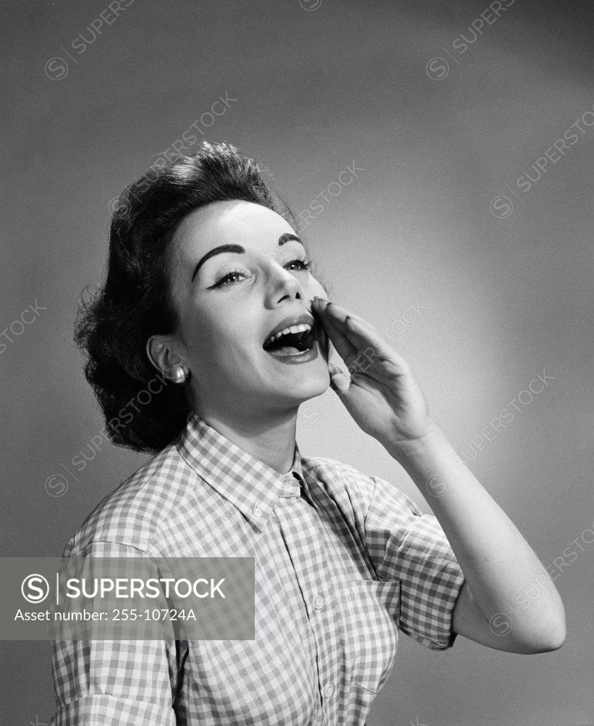 Stock Photo: 255-10724A Close-up of a young woman shouting with her hand close to her mouth