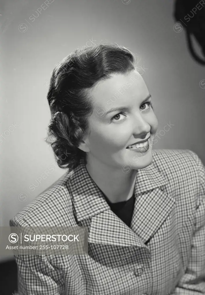 Brunette woman smiling wearing gingham plaid pattern jacket