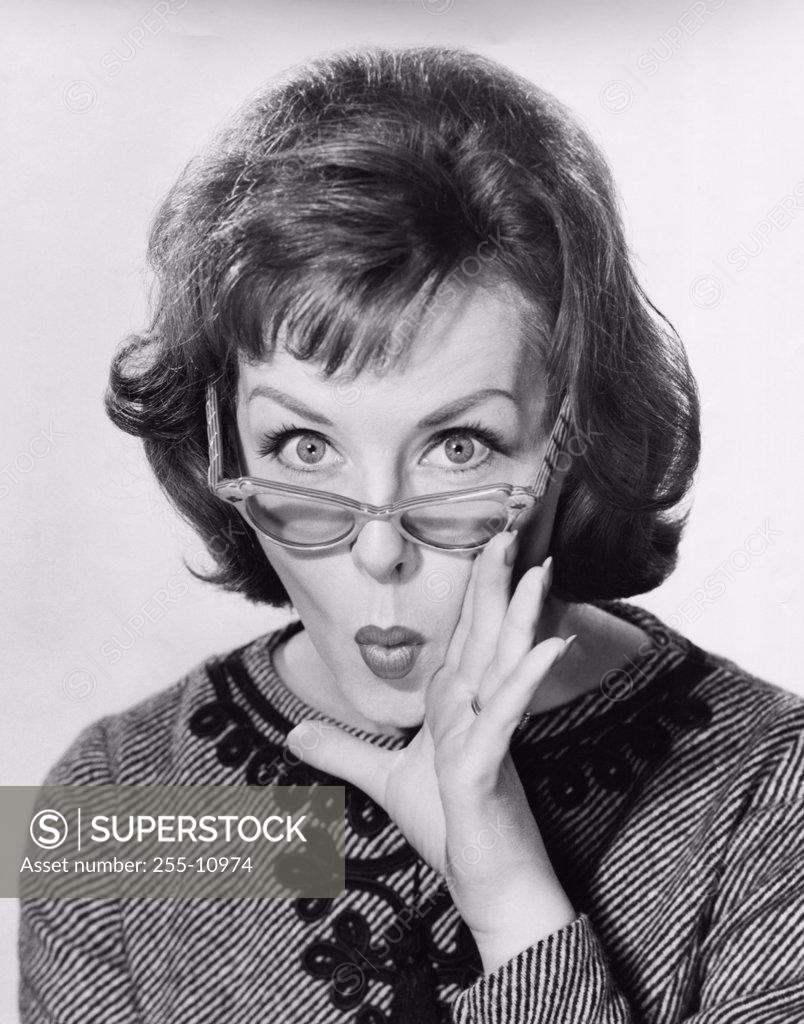 Stock Photo: 255-10974 Portrait of a young woman puckering with her hand close to her mouth