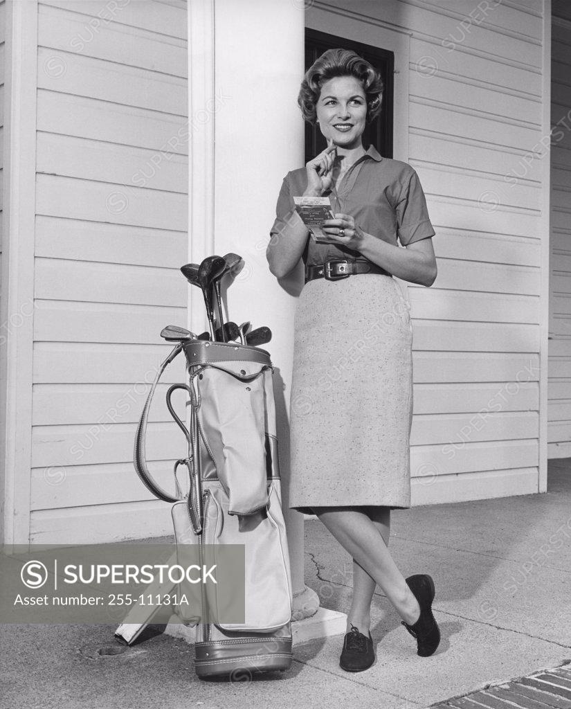 Stock Photo: 255-11131A Mid adult woman leaning against a column near a golf bag
