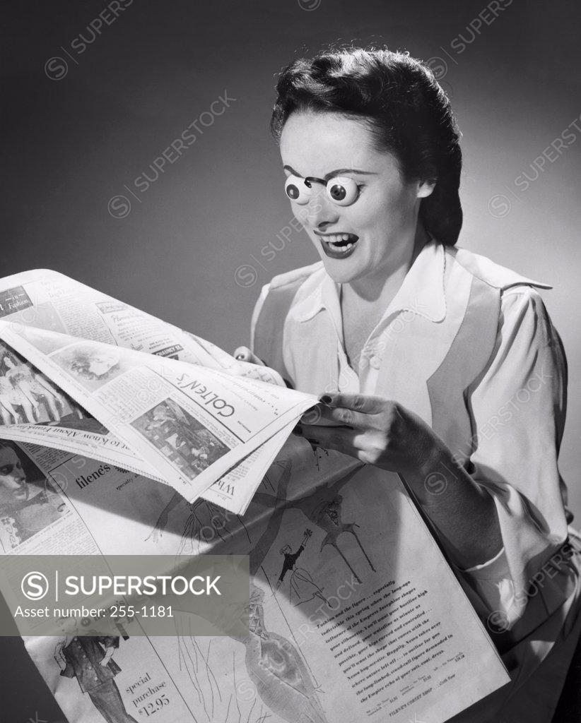 Stock Photo: 255-1181 Young woman reading a newspaper with her eyes popping out