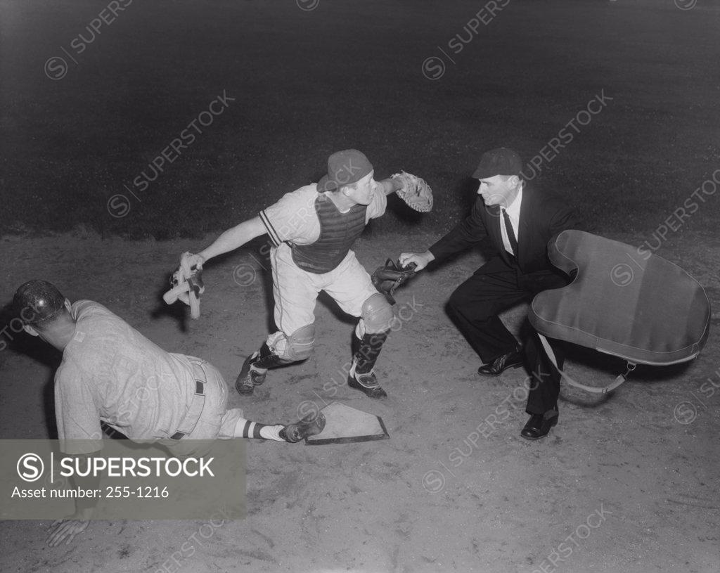 Stock Photo: 255-1216 Baseball player sliding on home base and a umpire calling him safe