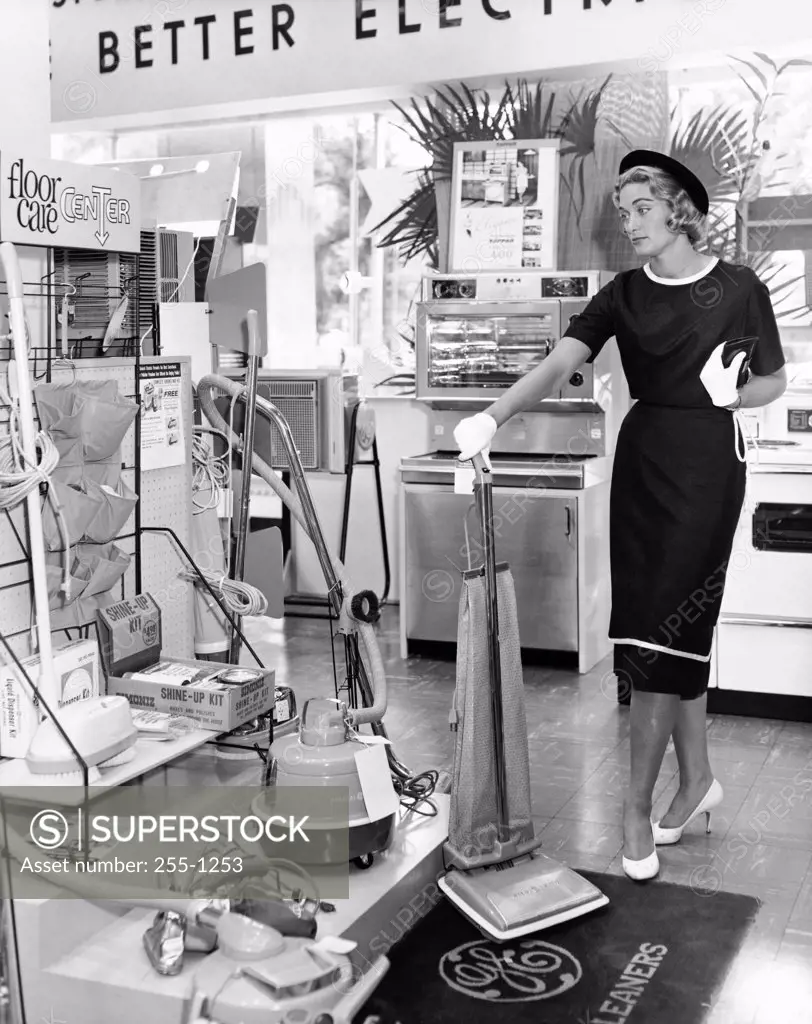 Young woman holding a vacuum cleaner in a store
