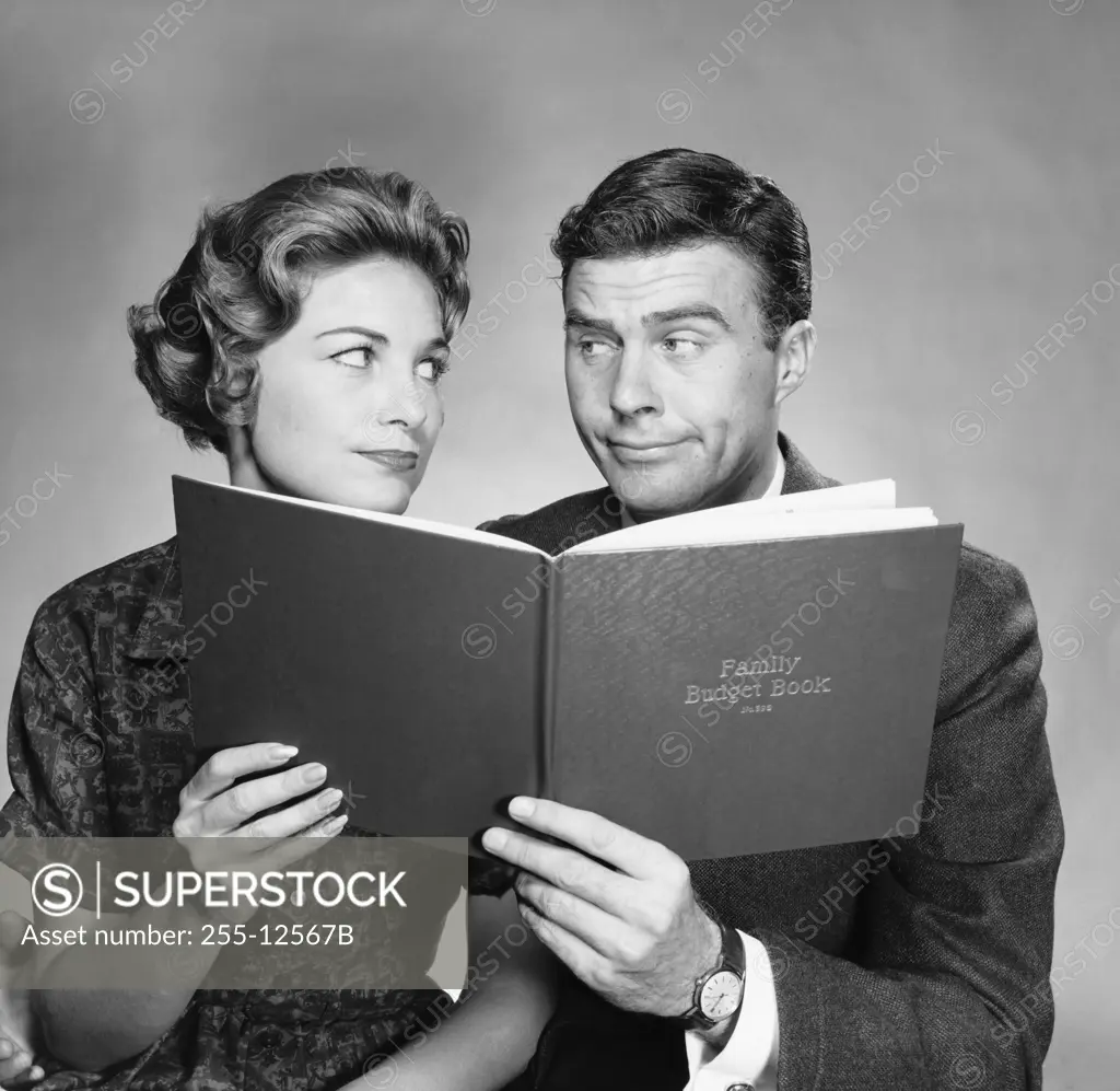 Close-up of a mid adult couple holding a family budget book