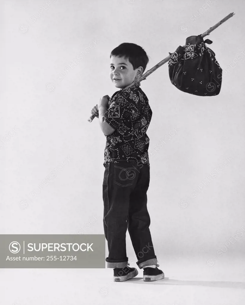 Rear view of a boy carrying a bundle on a stick