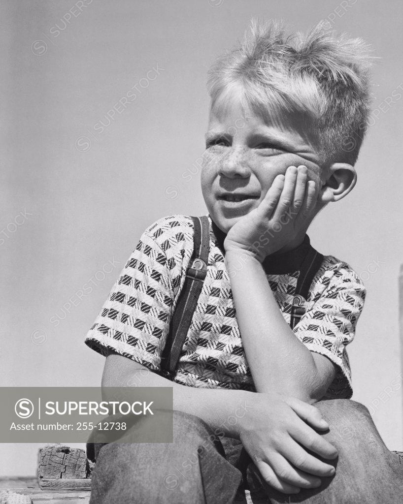 Stock Photo: 255-12738 Boy sitting with hand on chin