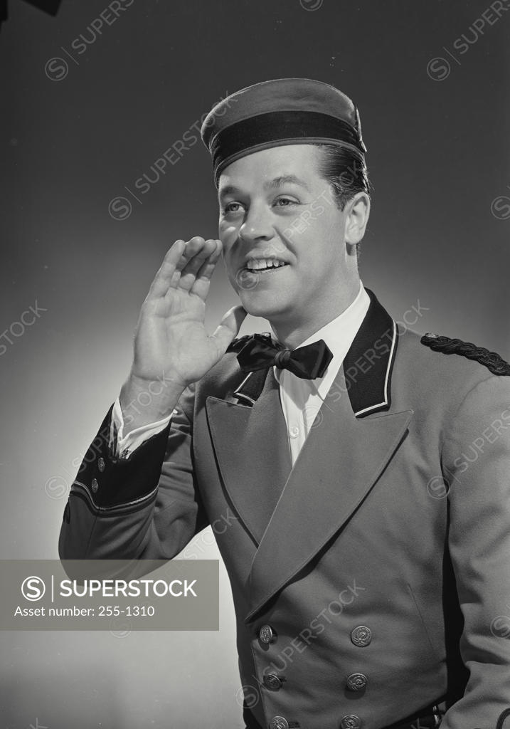 Stock Photo: 255-1310 Close-up of a bellhop talking with his hand near his mouth