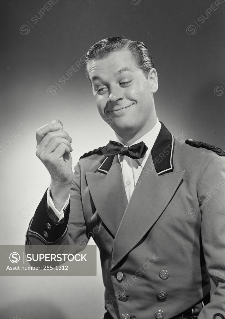 Stock Photo: 255-1312 Close-up of a bellhop smiling and holding a coin