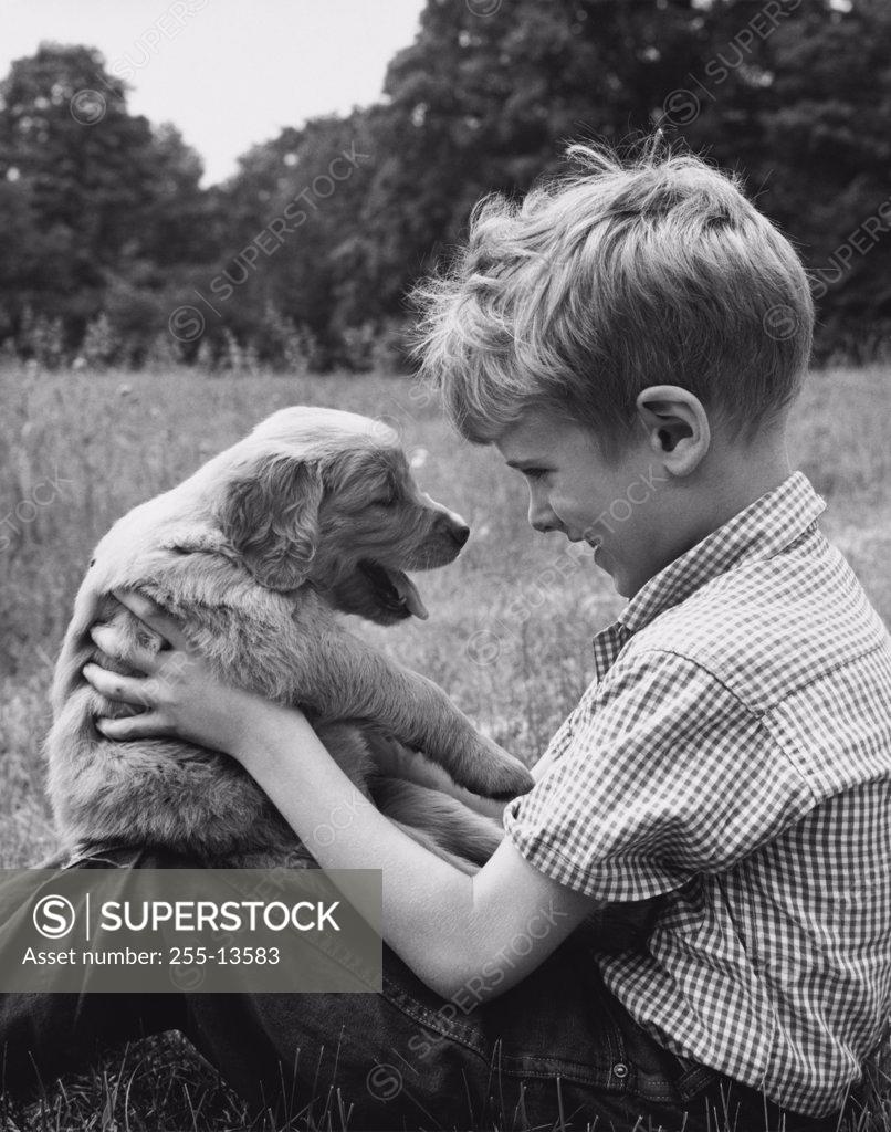 Stock Photo: 255-13583 Side profile of boy holding his puppy
