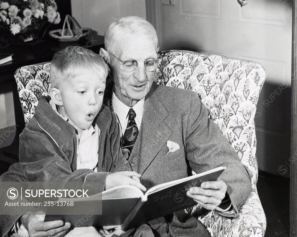Stock Photo: 255-1376B Close-up of a boy sitting on his grandfather's lap and reading a book
