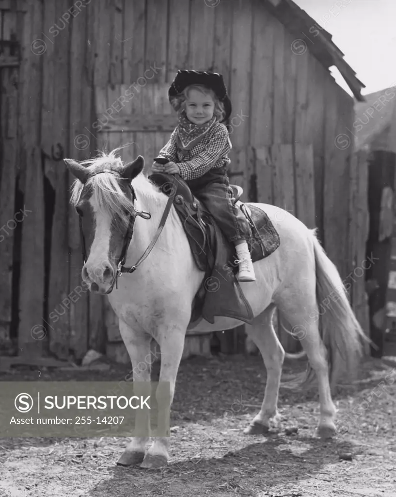 Girl sitting on a horse in front of a barn