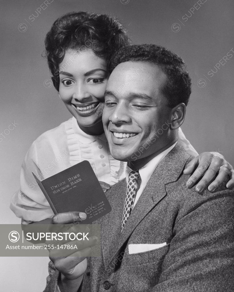 Stock Photo: 255-14786A Close-up of a young couple looking at a bankbook and smiling