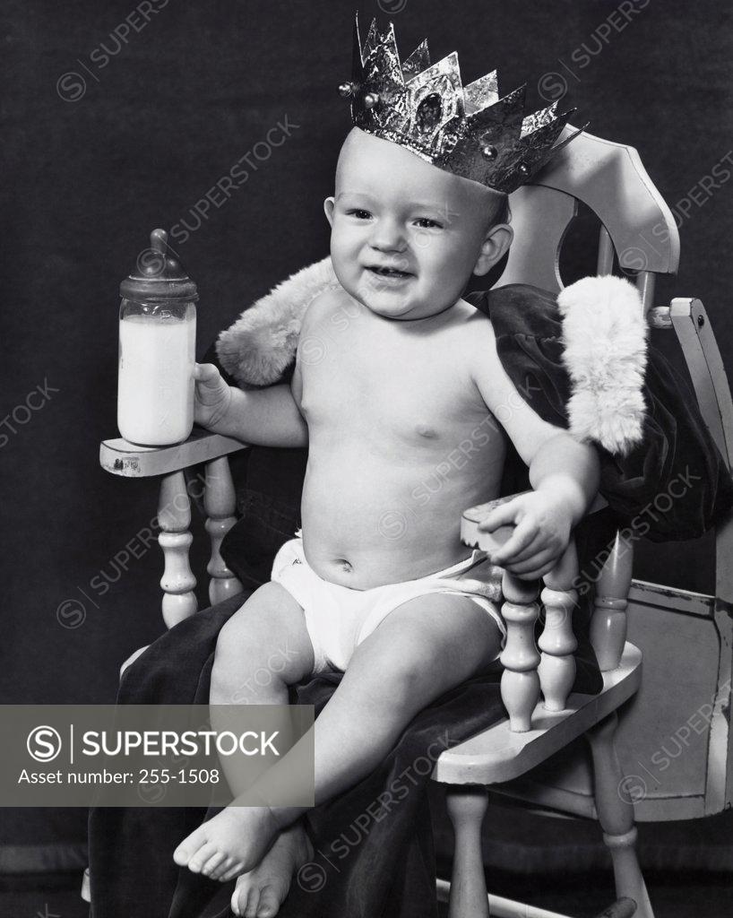 Stock Photo: 255-1508 Close-up of a baby boy wearing a crown sitting in an armchair
