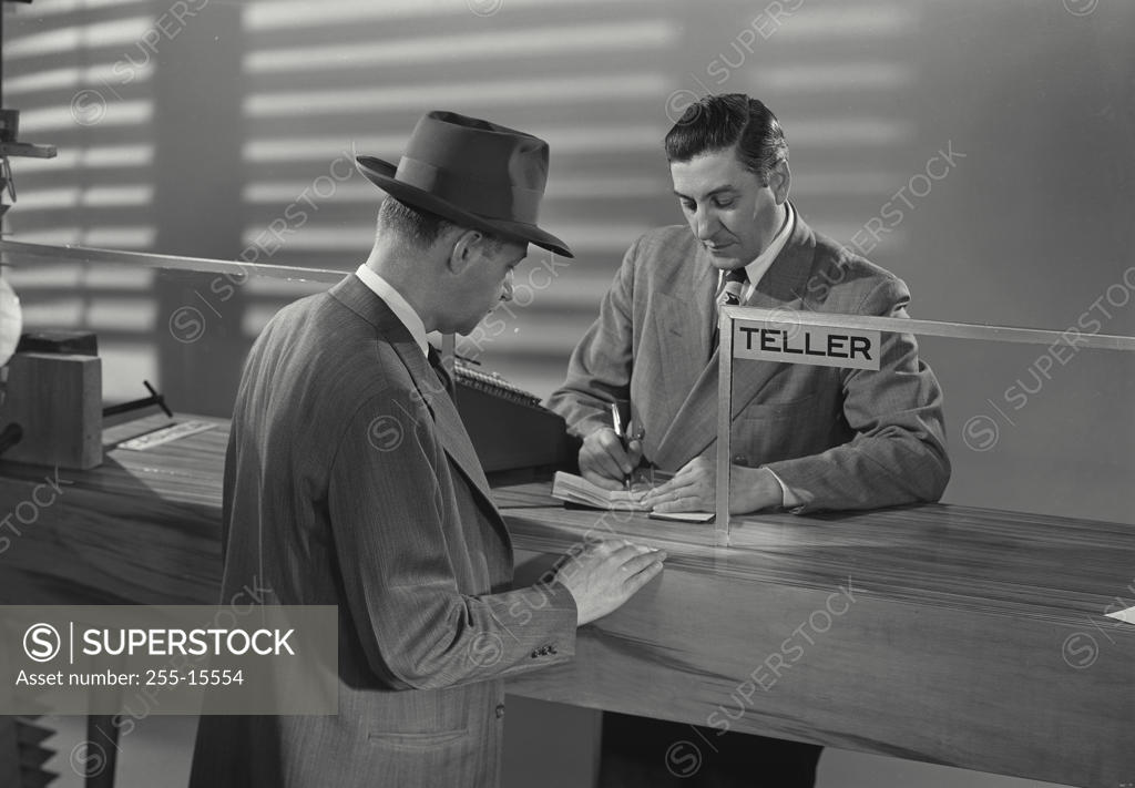 Stock Photo: 255-15554 Mature man standing in front of a bank teller in a bank