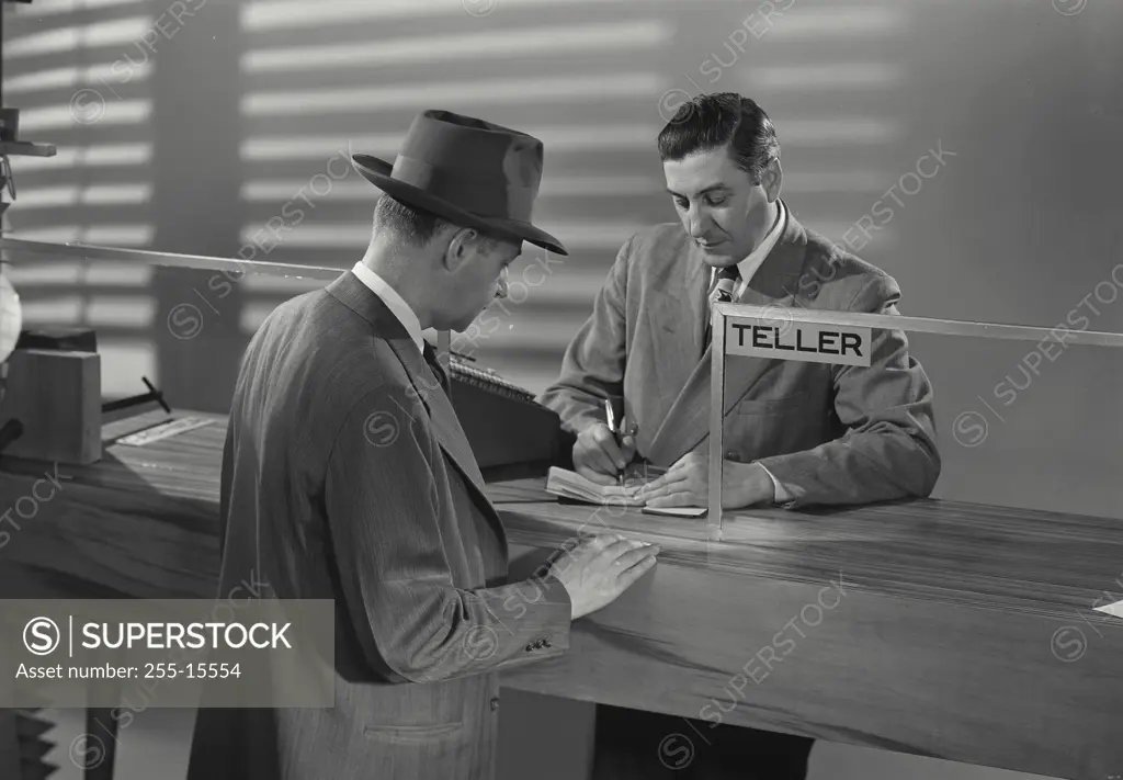 Mature man standing in front of a bank teller in a bank