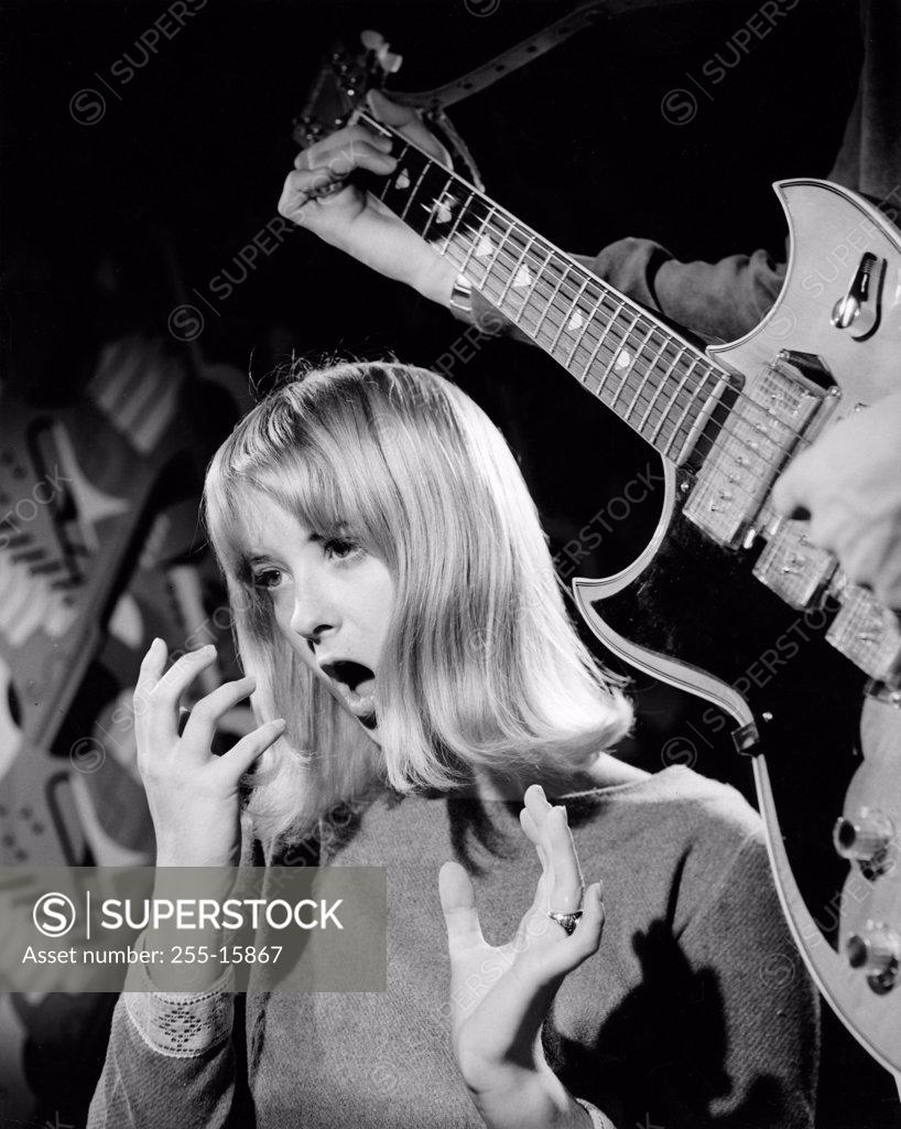 Stock Photo: 255-15867 Young woman singing with an electric guitarist