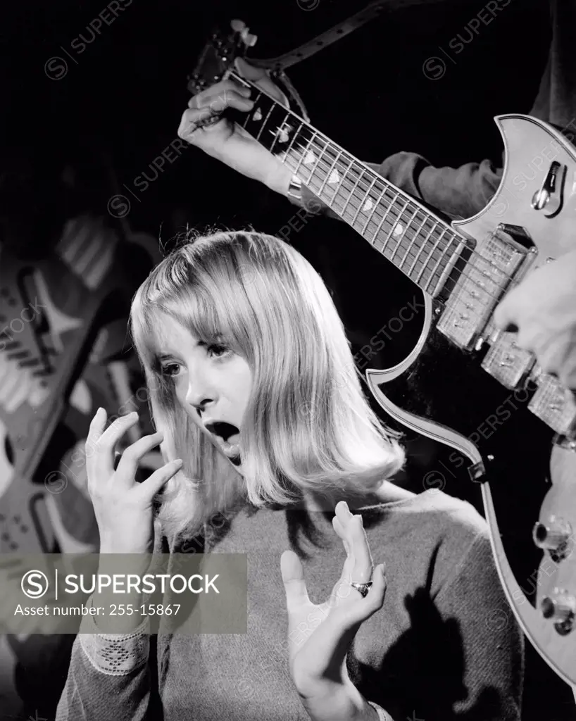Young woman singing with an electric guitarist
