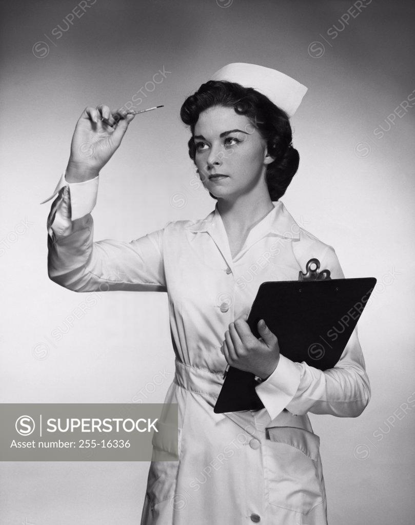 Stock Photo: 255-16336 Close-up of a female nurse reading a thermometer and holding a clipboard
