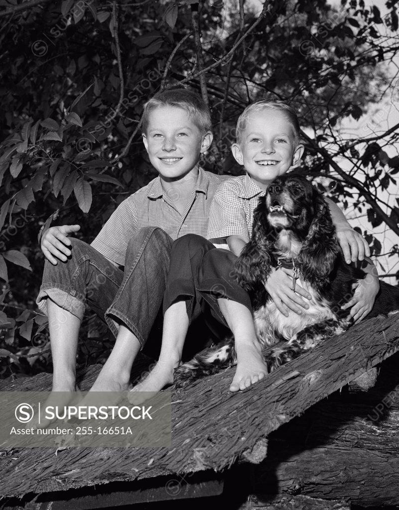 Stock Photo: 255-16651A Portrait of smiling boys sitting on roof with dog