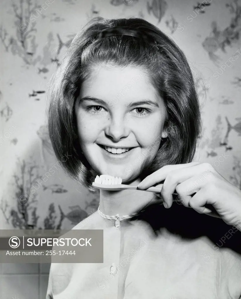 Portrait of a teenage girl holding a toothbrush and smiling, 1966