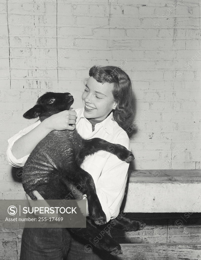 Stock Photo: 255-17469 Close-up of a teenage girl carrying a lamb and smiling