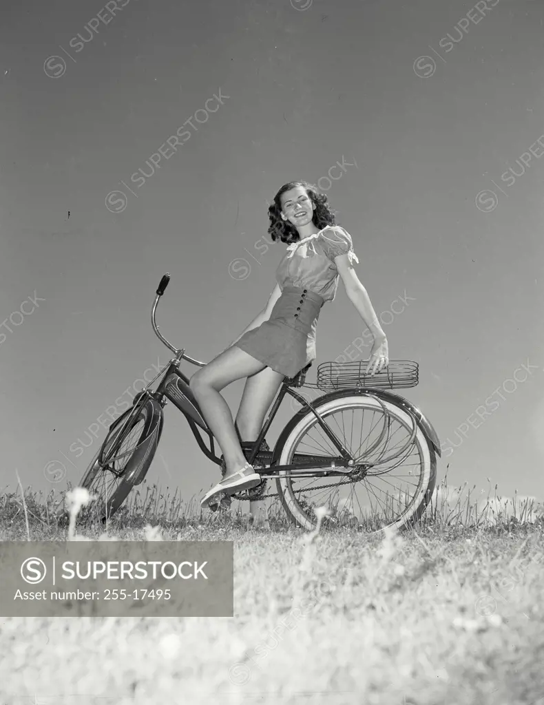 Vintage Photograph. Woman sitting on bicycle leaning back onto basket