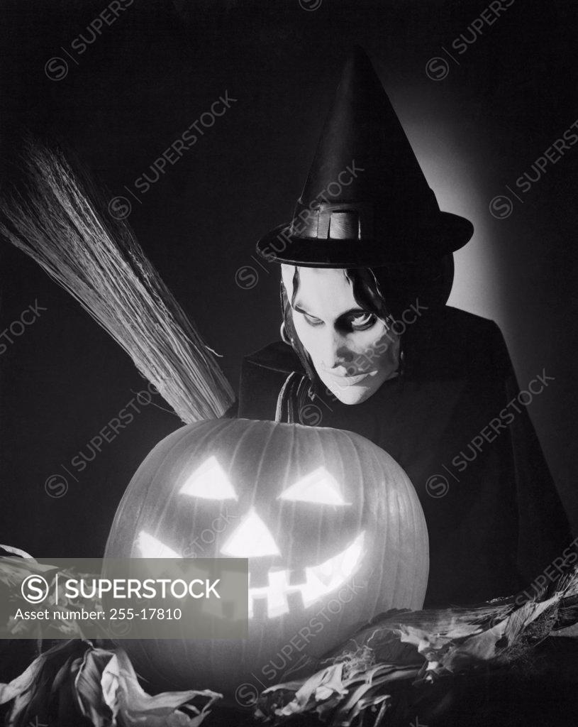 Stock Photo: 255-17810 Close-up of an illuminated jack o' lantern with a person wearing a Halloween costume behind it