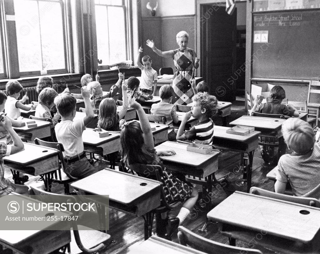 Stock Photo: 255-17847 Group of students raising their hands in a classroom