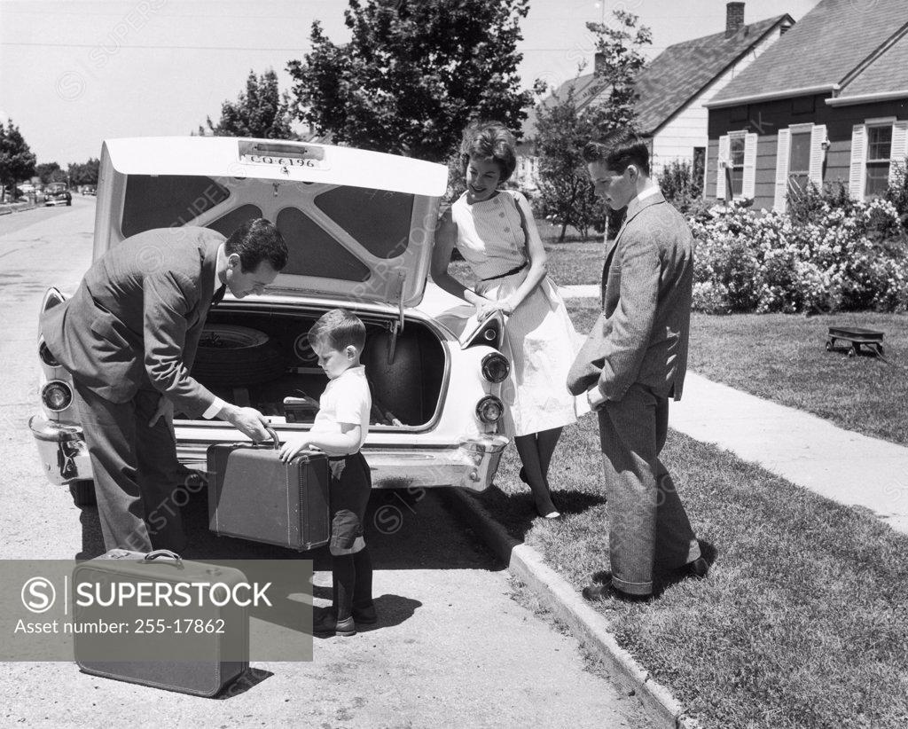 Stock Photo: 255-17862 Parents and their children loading luggage into a car
