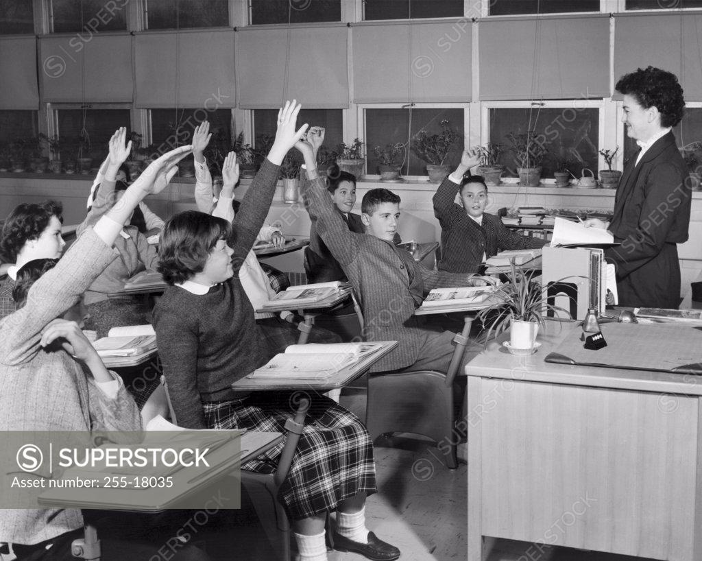 Stock Photo: 255-18035 Group of students raising their hands in a classroom