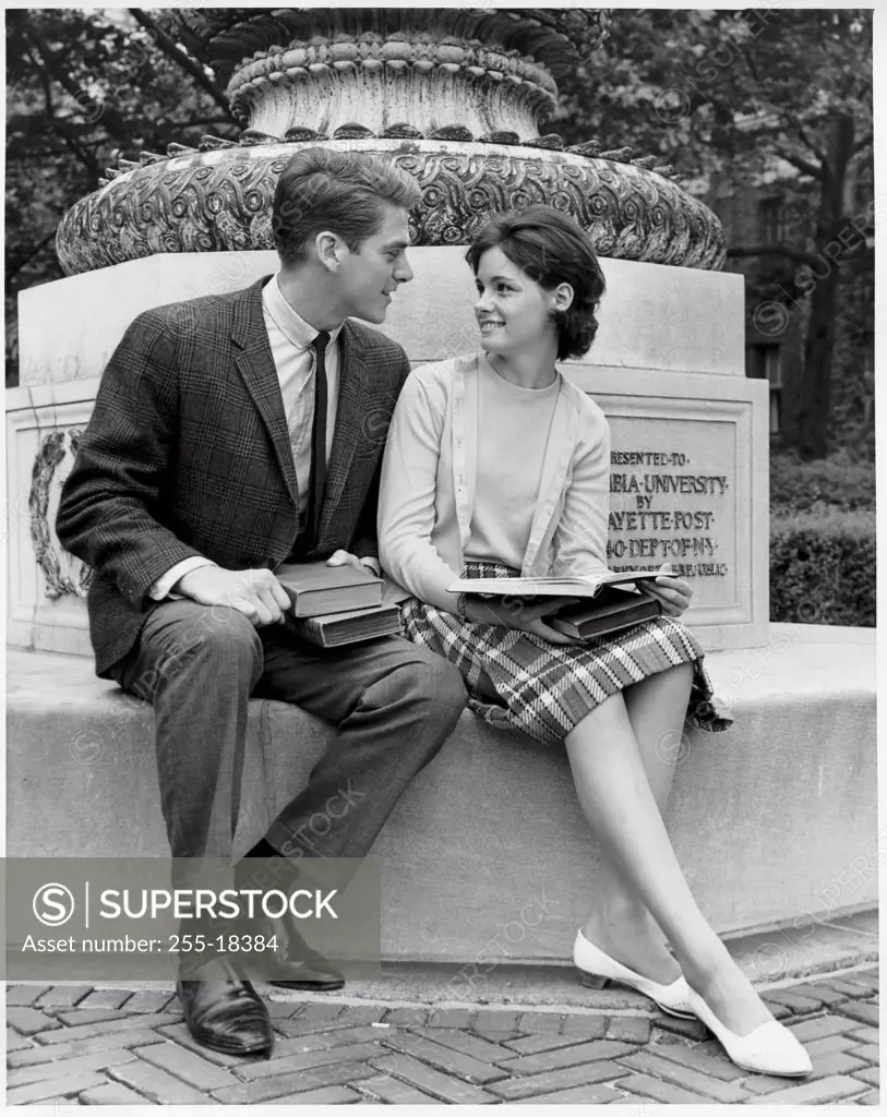 Young couple sitting on a pedestal looking at each other