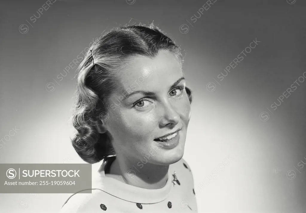Vintage photograph. Woman with short hair in polka dot blouse smiling.