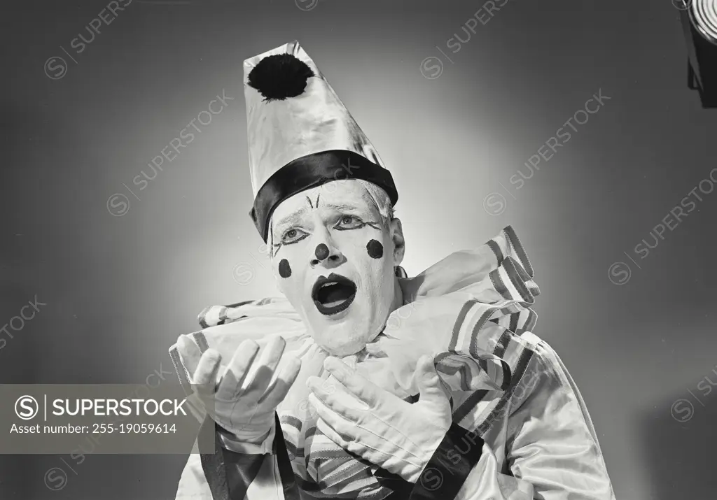 Vintage photograph. Portrait of clown in silly hat with mouth open.
