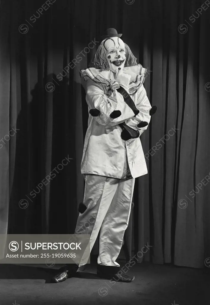 Vintage photograph. Portrait of clown wearing silly hat with hand on chin