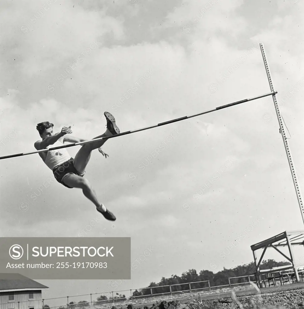 Vintage photograph. High bar jump athlete mid jump