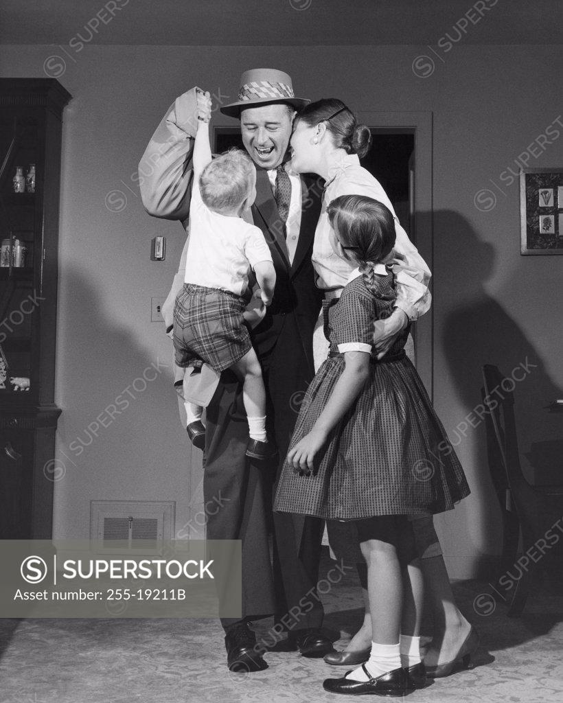 Stock Photo: 255-19211B Mid adult couple standing in a room with their son and daughter