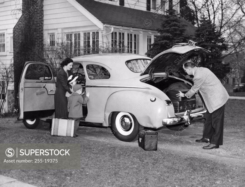 Stock Photo: 255-19375 Mid adult couple with their children loading luggage into a car