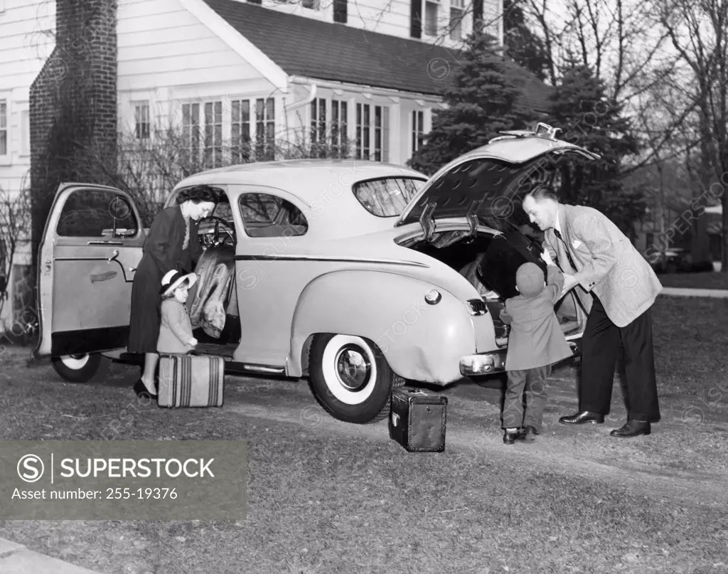 Parents and their children loading luggage into a car