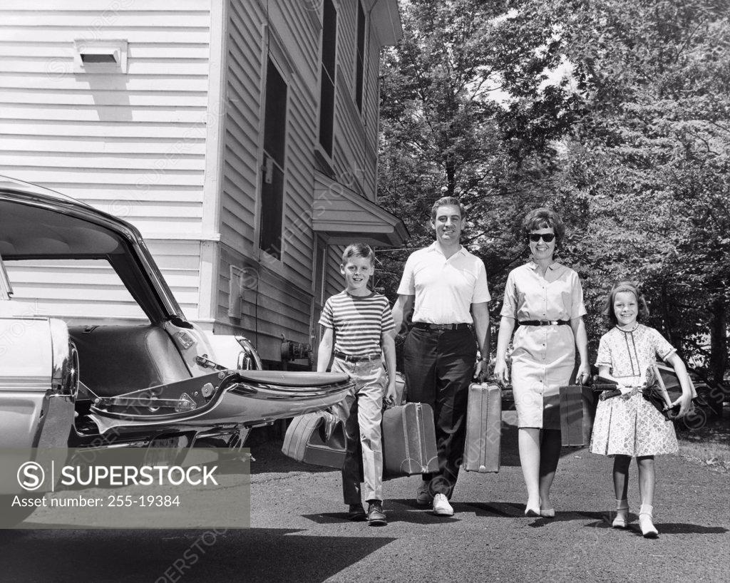 Stock Photo: 255-19384 Family carrying luggage towards a car