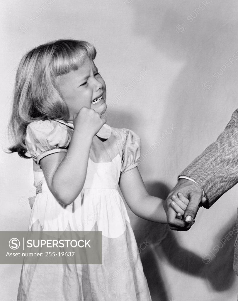 Stock Photo: 255-19637 Close-up of a girl holding her father's hand and crying