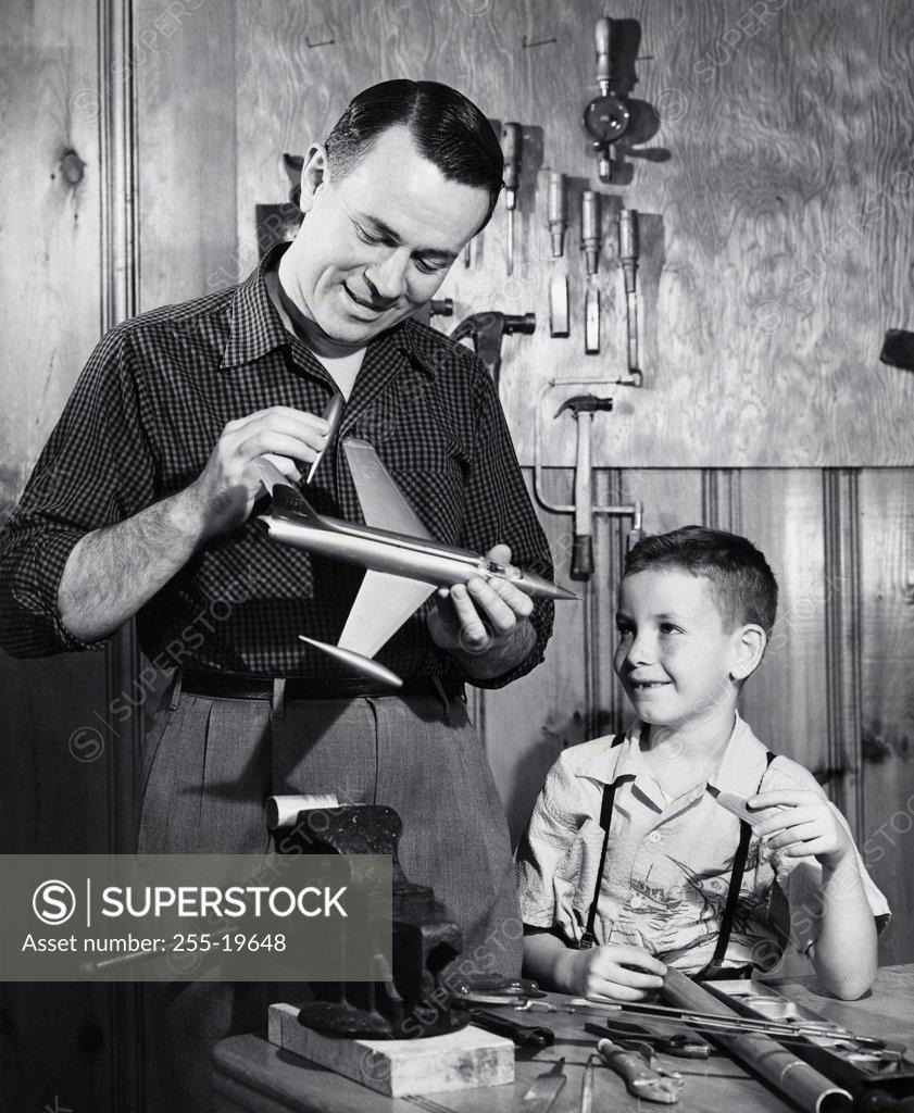 Stock Photo: 255-19648 Father repairing a model airplane with his son standing beside him