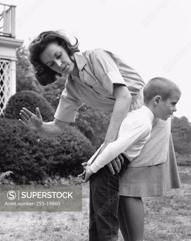 Stock Photo: 255-19860 Mid adult woman spanking her son