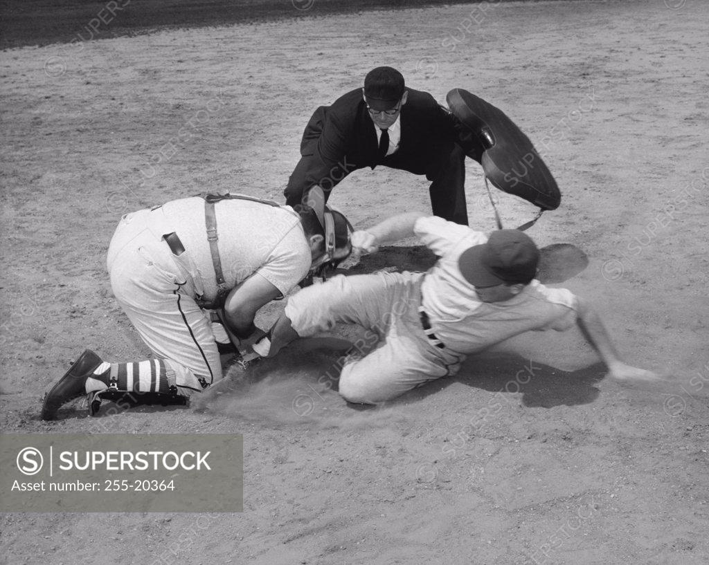 Stock Photo: 255-20364 Baseball player sliding on home base and a catcher trying to tag him