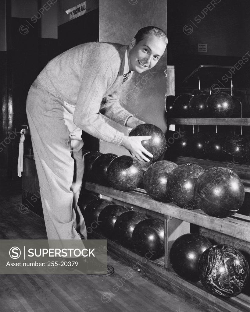 Stock Photo: 255-20379 Young adult man choosing a bowling ball