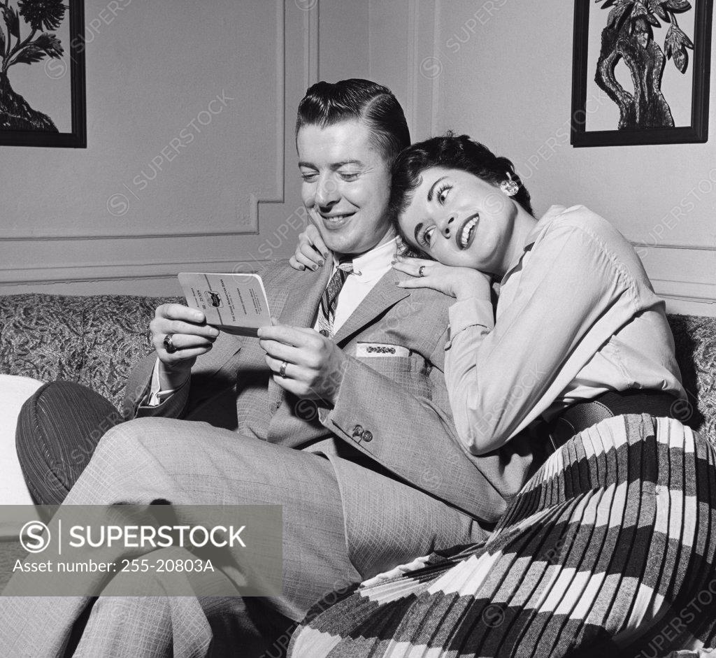 Stock Photo: 255-20803A Close-up of a mid adult couple sitting on a couch and reading a bankbook