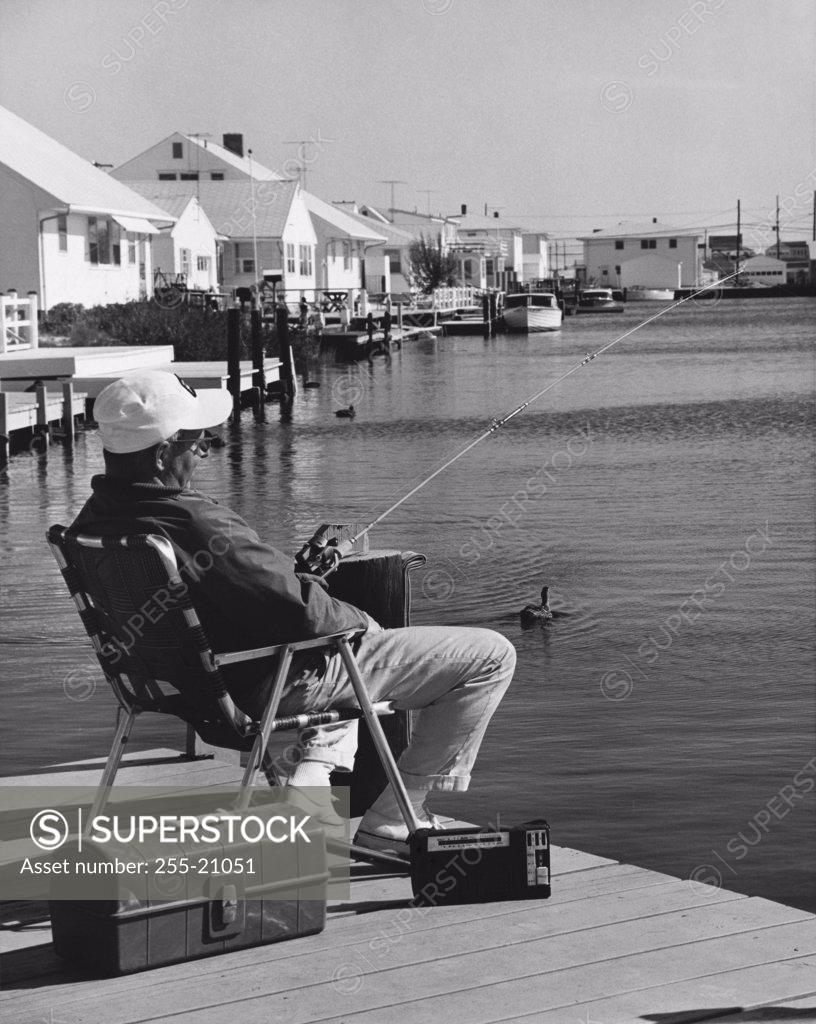 Stock Photo: 255-21051 Mature man sitting in armchair and fishing in lake